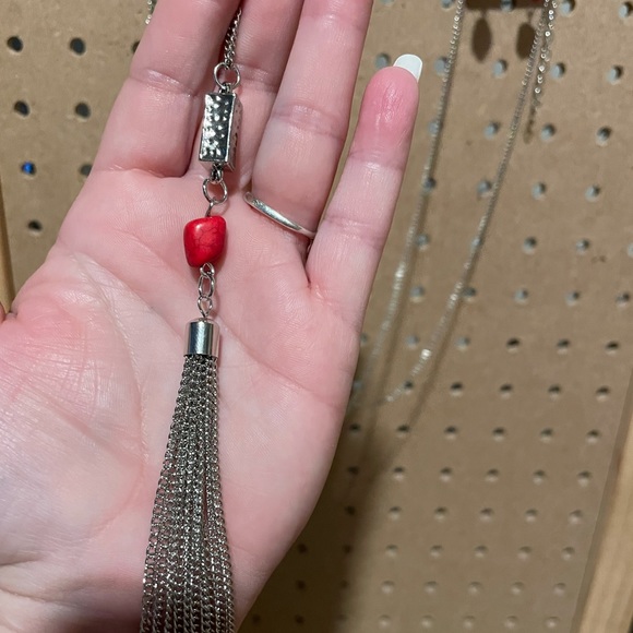 Long silver necklace with a silver triangle, red crackle, and fringe.